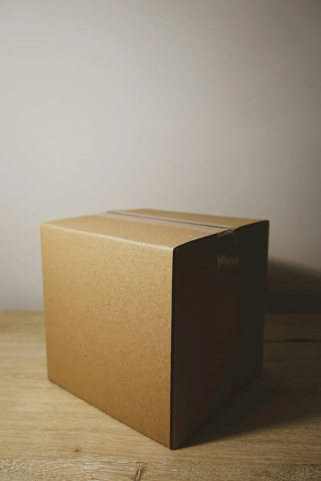 A plain cardboard box on a wooden table