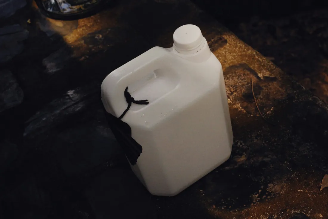 An unbranded white five-litre container on a dark table